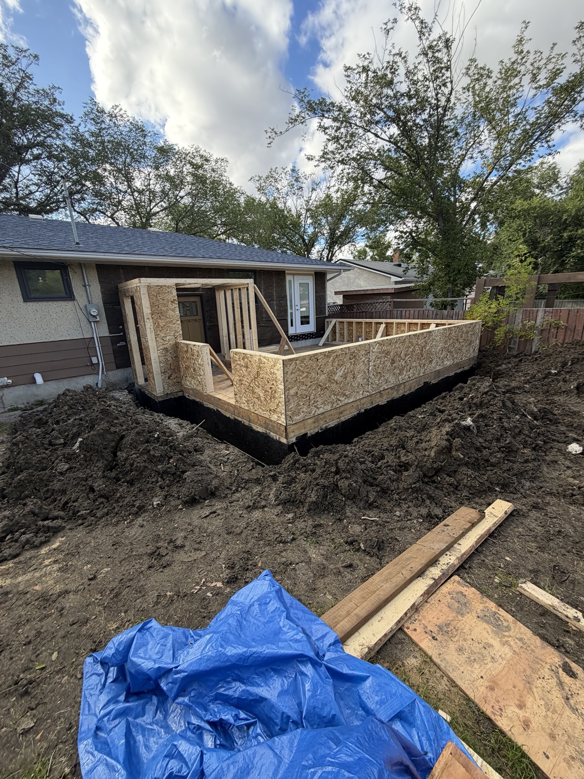 Sunroom construction with exterior wall sheathing beside a bungalow
